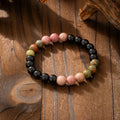 Long natural stone beaded sweater chain necklace and matching bracelet in bohemian style on a grey background.
