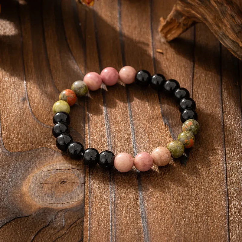 Long natural stone beaded sweater chain necklace and matching bracelet in bohemian style on a grey background.
