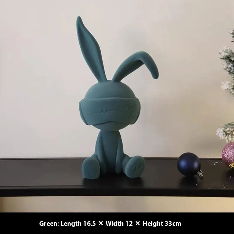 Suede blindfold rabbit resin table ornament in blue, green, or red colour on a shelf.