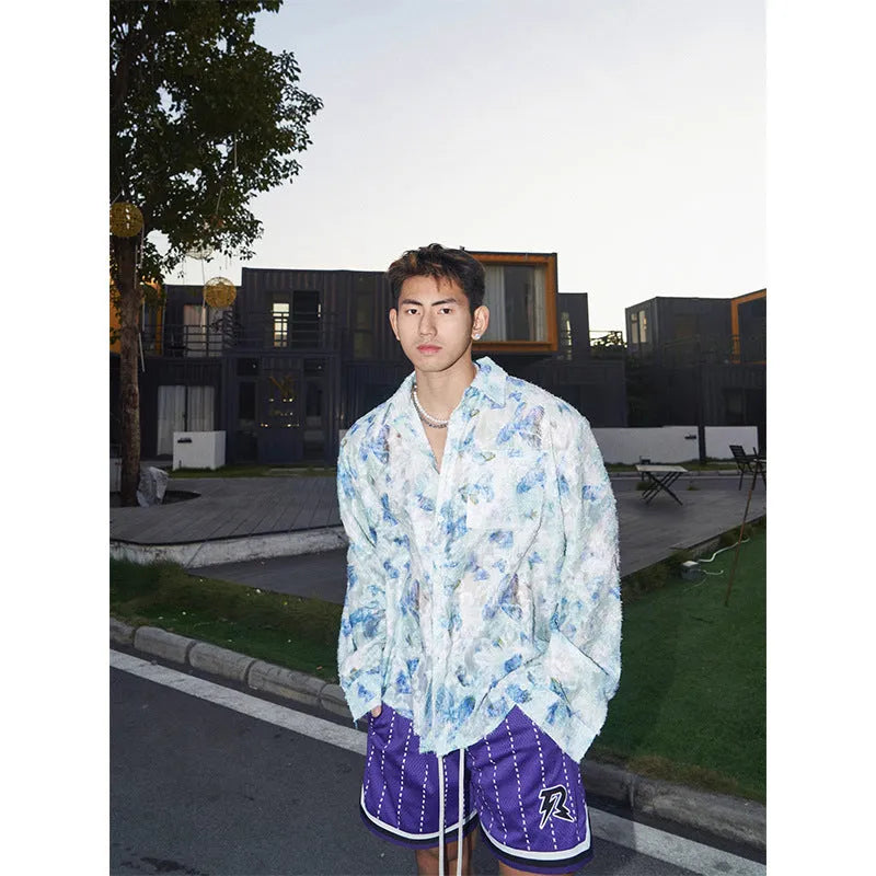 Man wearing a blue loose-fit long sleeve shirt with an embossed three-dimensional floral pattern.