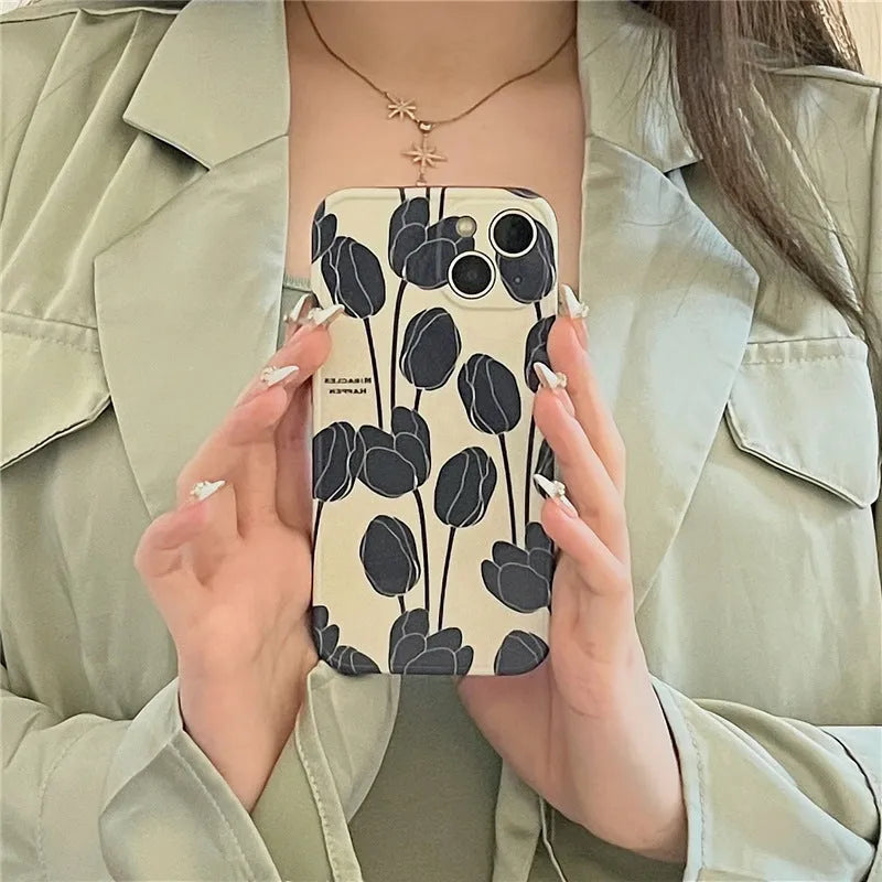 Black silicone iPhone case with a white tulip pattern design on the back.