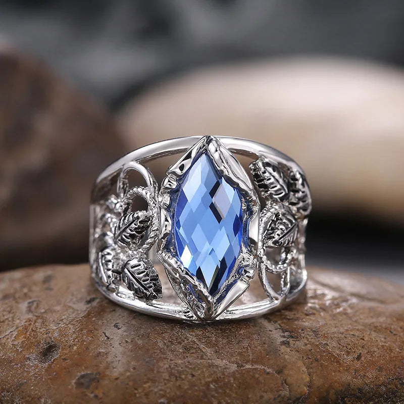 Blue crystal inlay on a geometric horse eye-shaped alloy ring for women.