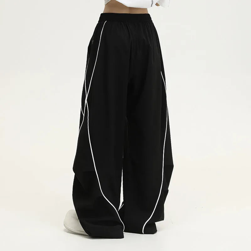 Black and white striped wide-leg hip hop sports trousers with pleats, shown laid flat.