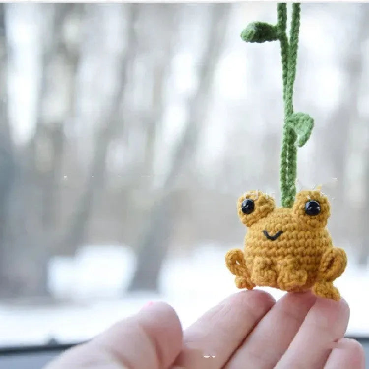 Handmade woven car pendant with a green frog plush doll hanging.