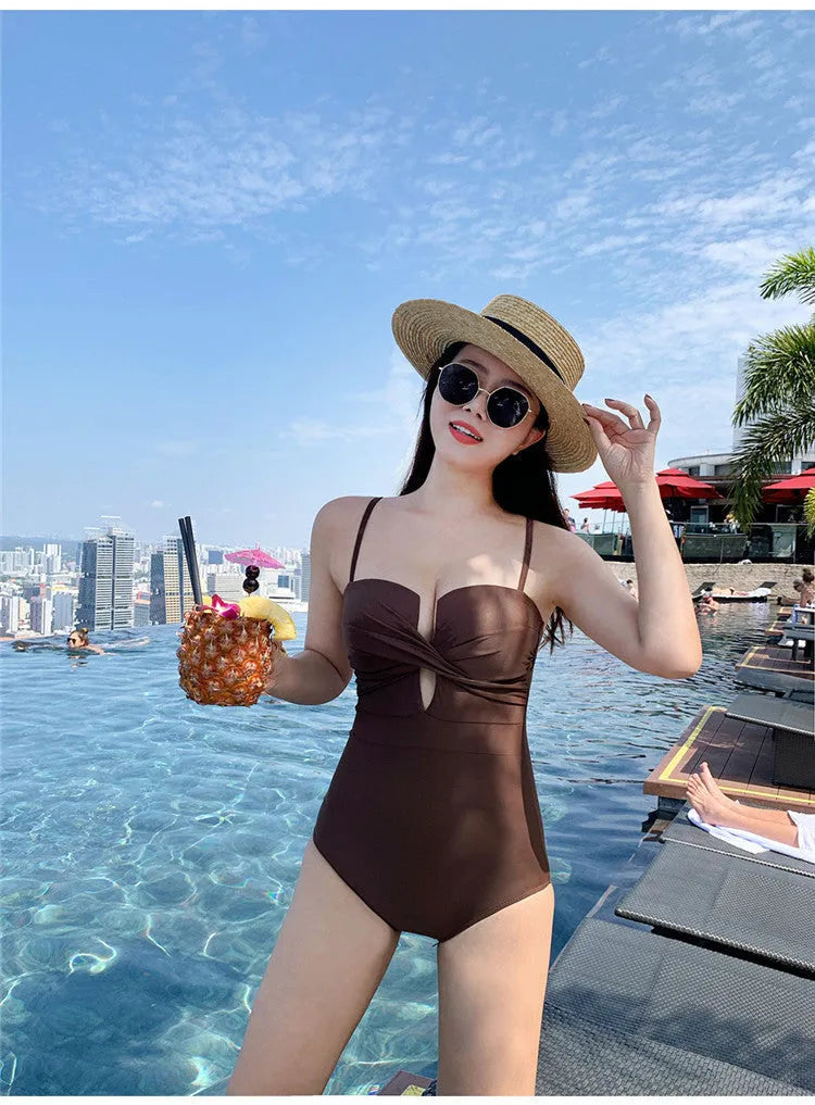 Women's solid colour one-piece swimsuit with spaghetti straps and push-up design in white, pink, or brown.