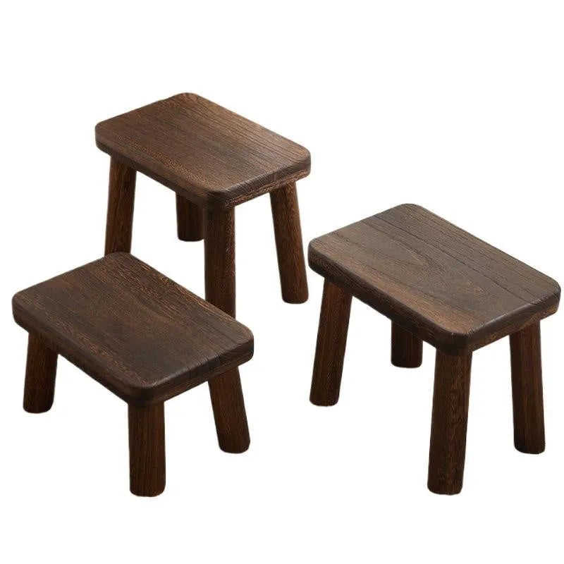 Distressed solid wood shoe changing stool with bracket structure, shown in a hallway setting.