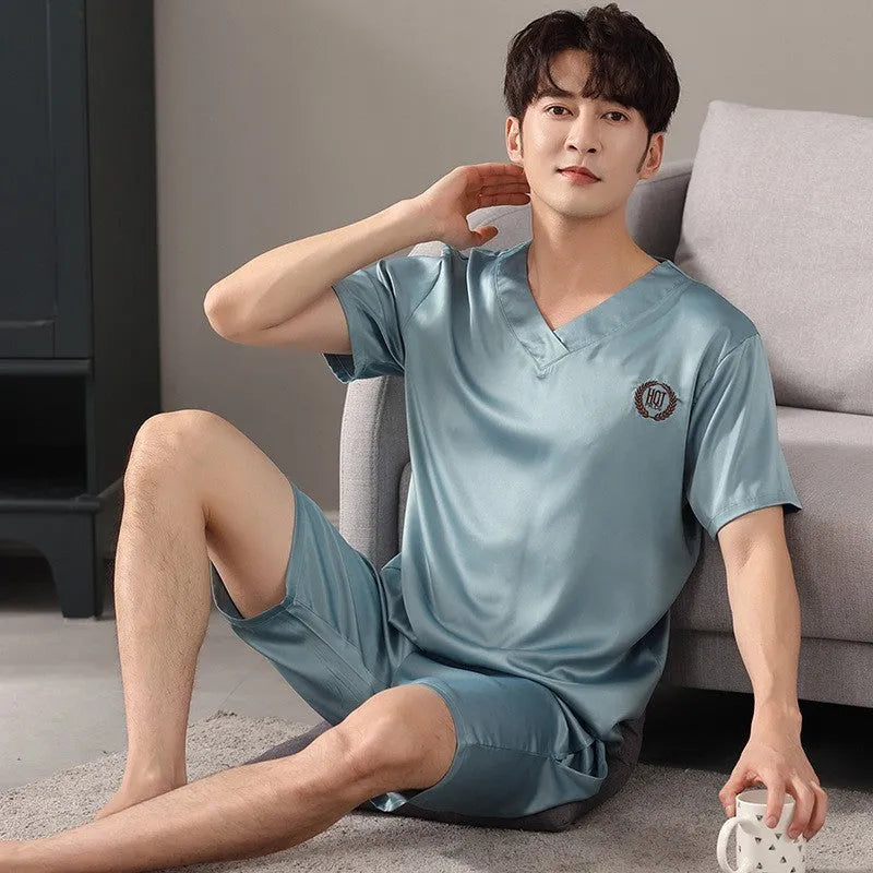 Man wearing a loose light blue short-sleeve pajama shirt and matching shorts, labelled as ice silk sleepwear.