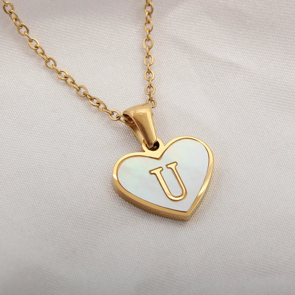 Gold plated heart-shaped white shell pendant personalised initial necklace on a stainless steel chain.