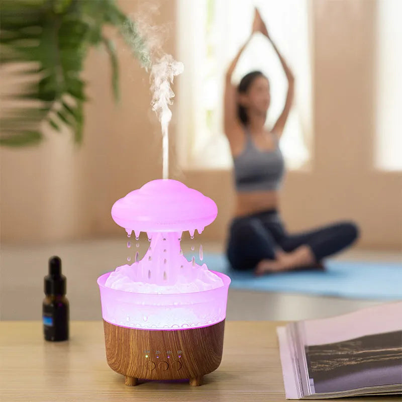 Wood grain green rain cloud shaped humidifier diffuser with coloured LED light on a table.