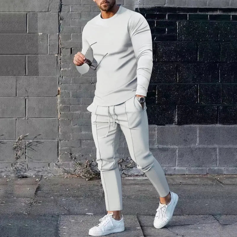 Man wearing a light grey round-neck long-sleeve t-shirt and matching trousers from a two-piece polyester suit set.