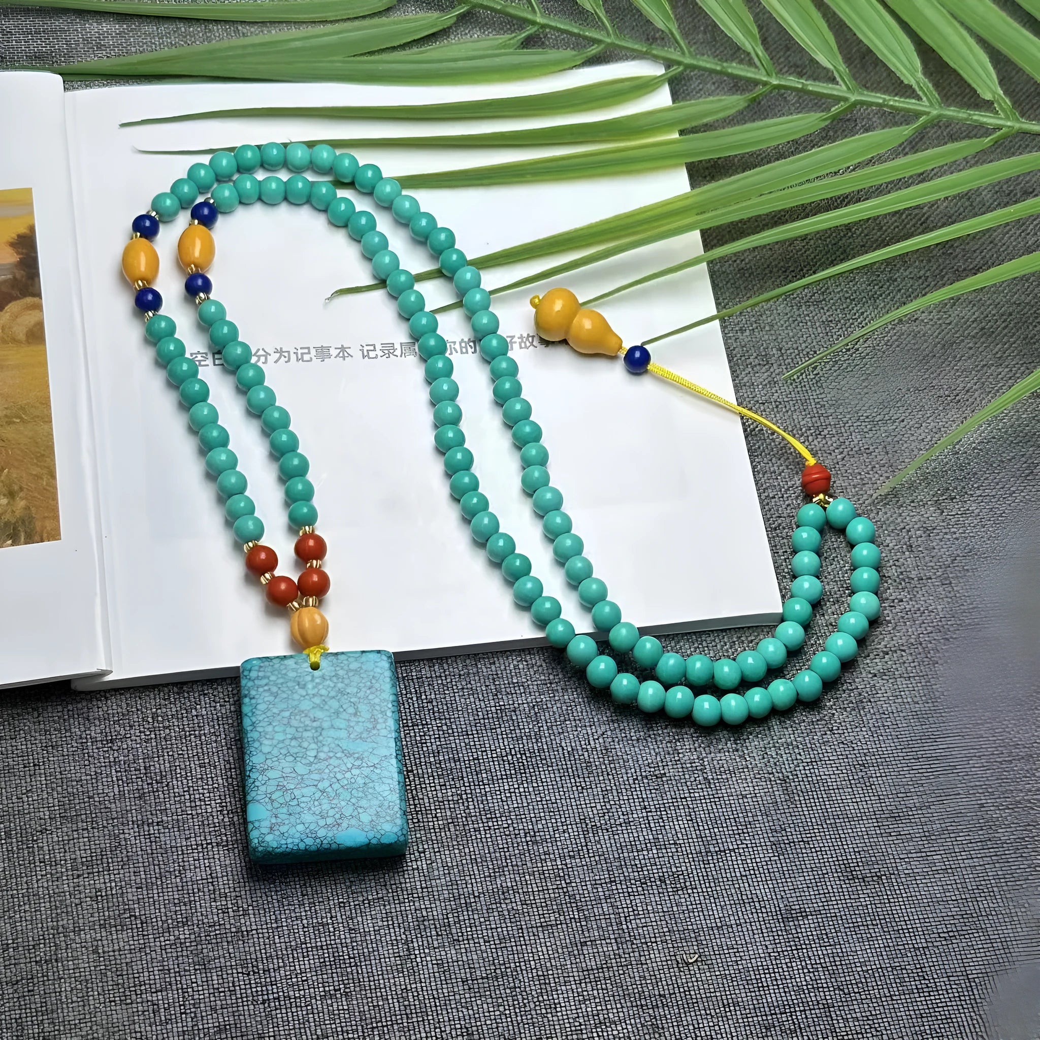 Turquoise lucky pendant necklace with hand-woven mesh flower design on ball bead chain