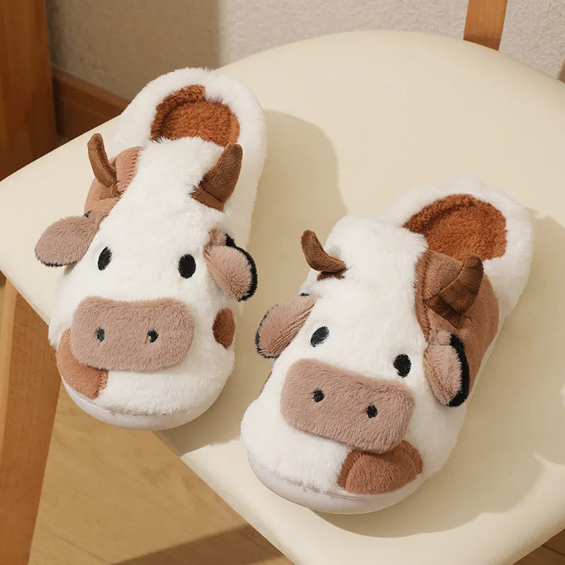 White cow-themed faux fur slippers with plush lining and textured non-slip soles.