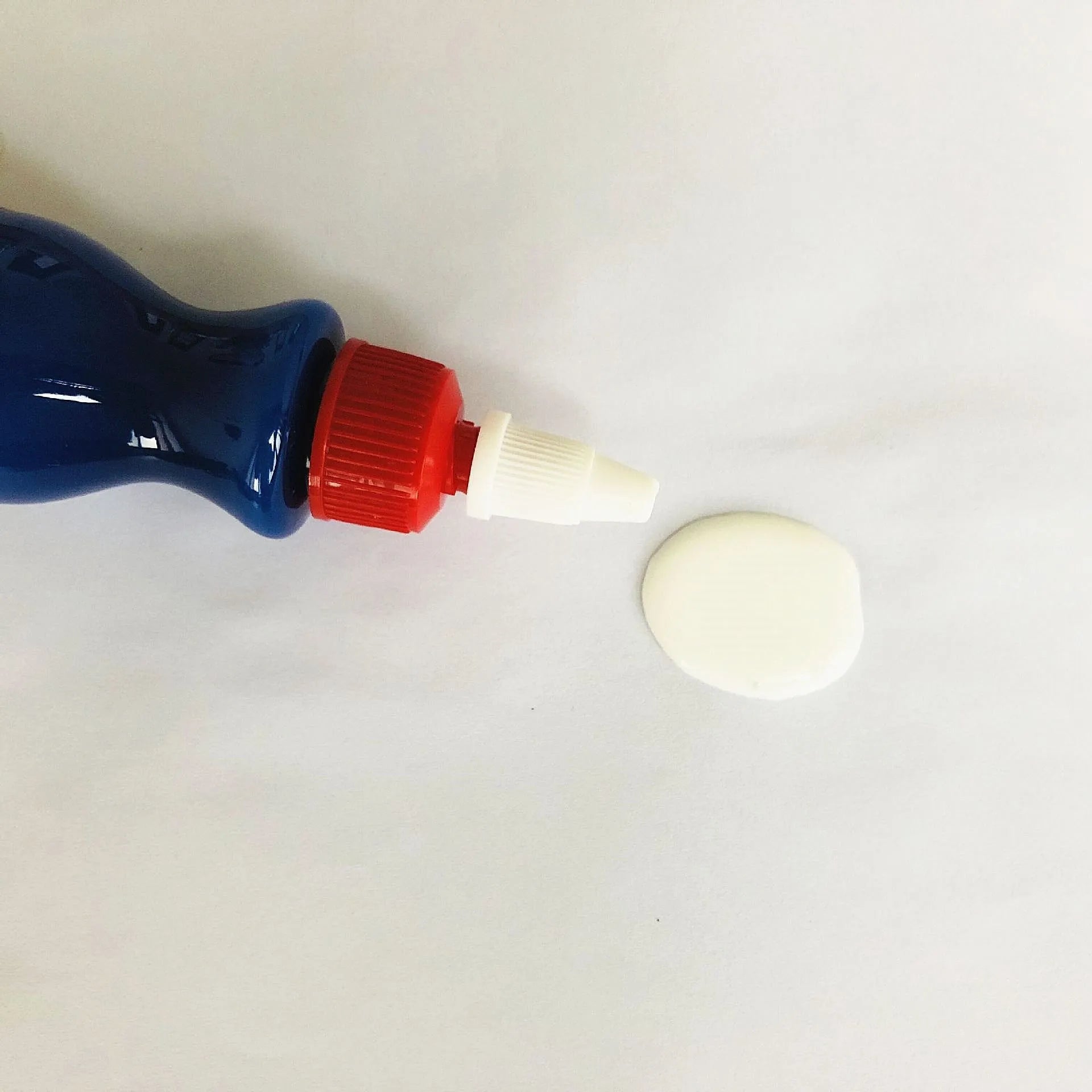 Small blue container of scratch repair agent with integrated wiping tool for automotive paint
