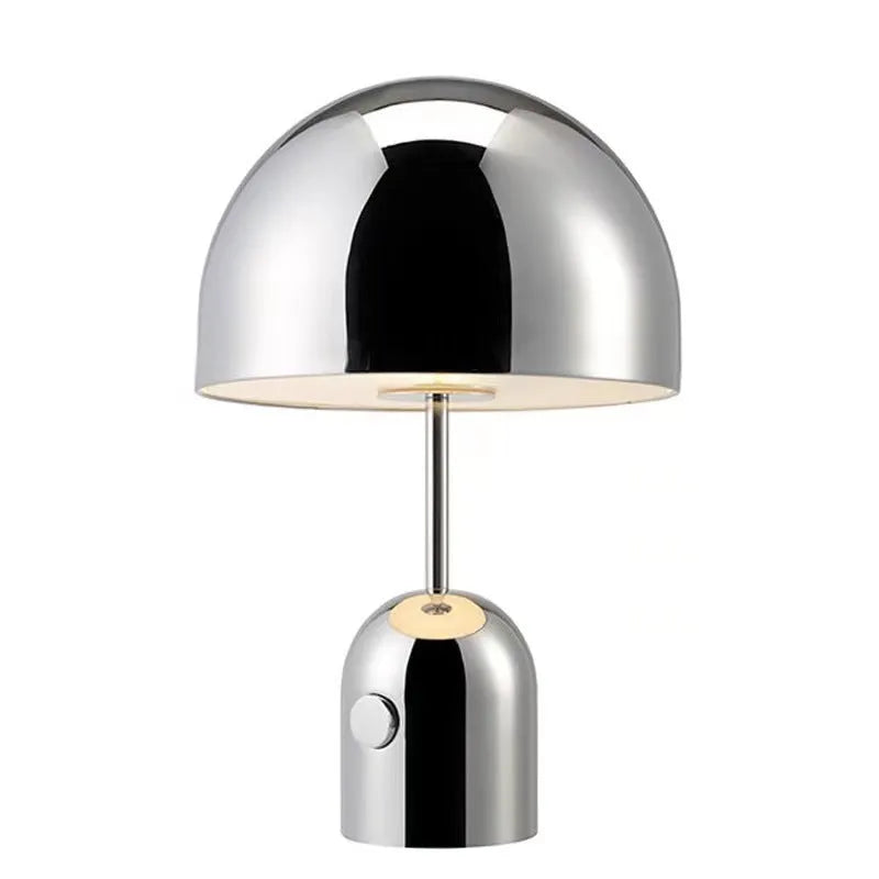 Mushroom-shaped table lamp with a metal base in rose gold finish on a wooden surface.