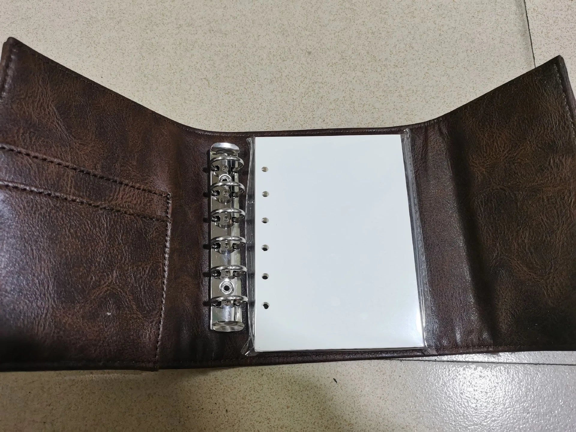 Brown retro notebook with buckle closure showing loose-leaf binding and A7 size