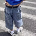 Man wearing blue washed denim high waist pirate shorts with a cropped, straight leg