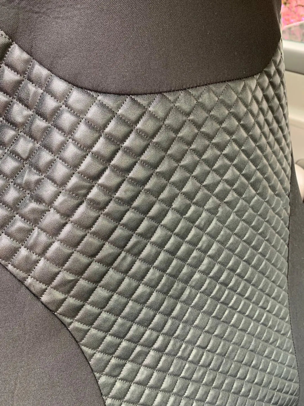 Black quilted automotive seat cover made from PU and polyester fabric, shown with plastic attachment hooks.