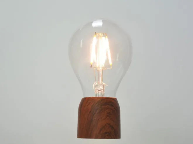 Magnetic levitation floating light bulb with UK plug on imitation wood base.