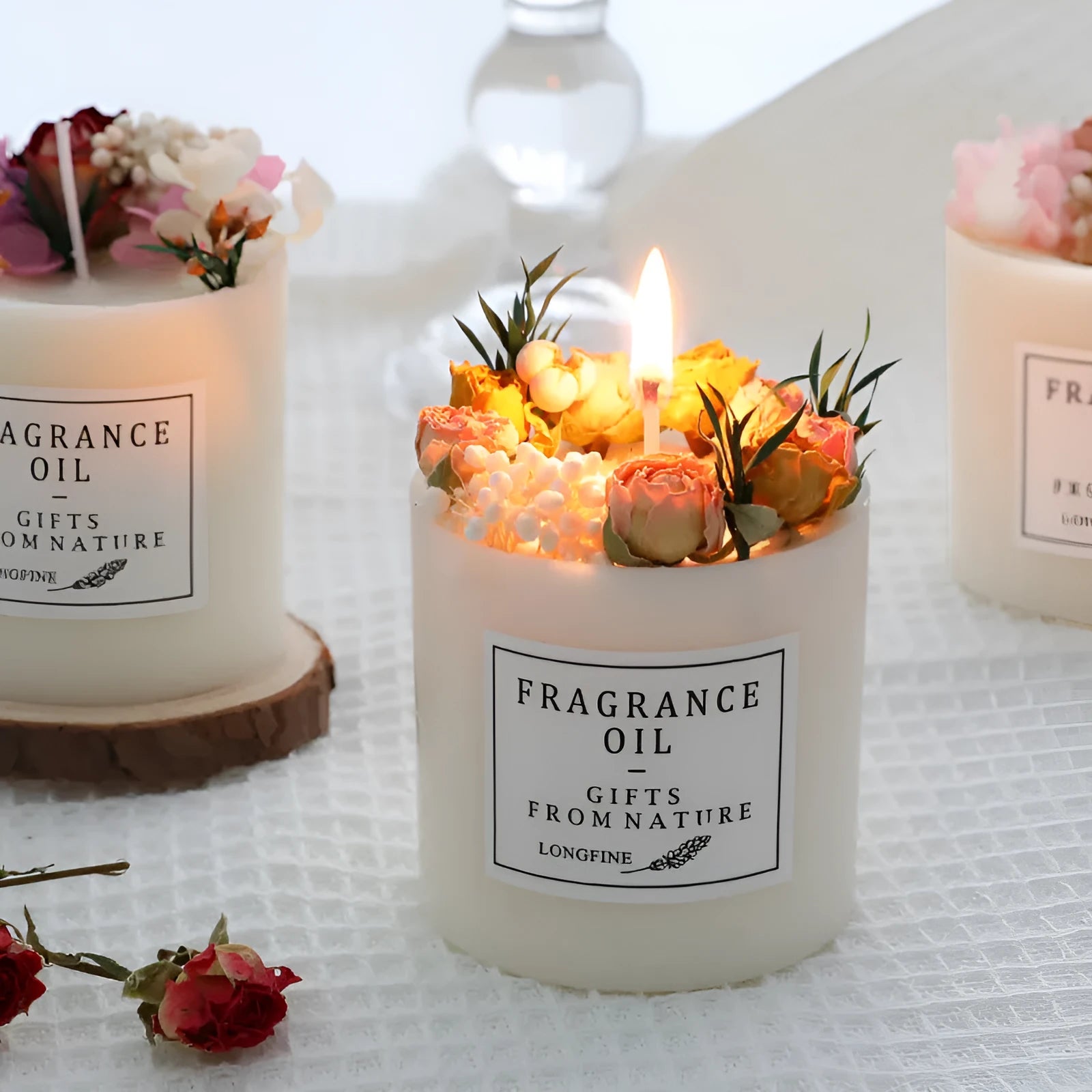 Aromatherapy candle decorated with dried flowers on top, shown in gift box packaging with a wood base.