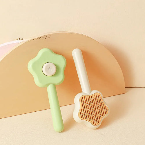 Green self-cleaning cat comb with stainless steel needle pins on a white background