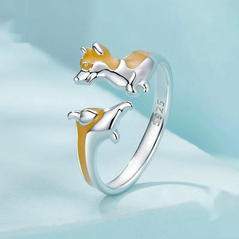 Silver corgi pet cartoon ring with electroplated colour on a model's finger.