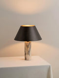 Black modern table lamp with a marble base on a wooden desk.