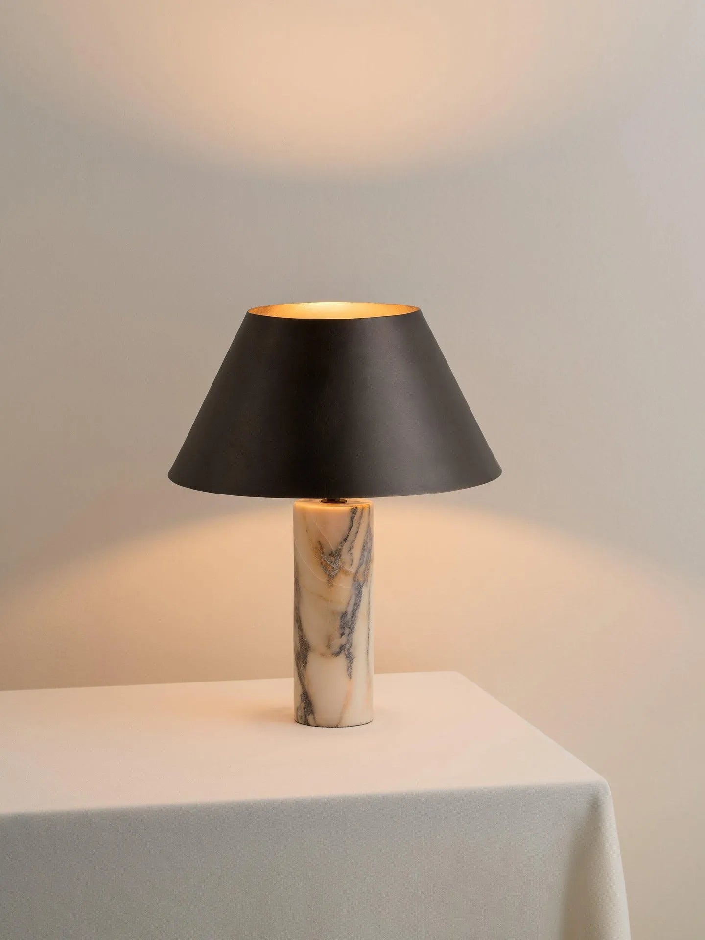 Black modern table lamp with a marble base on a wooden desk.