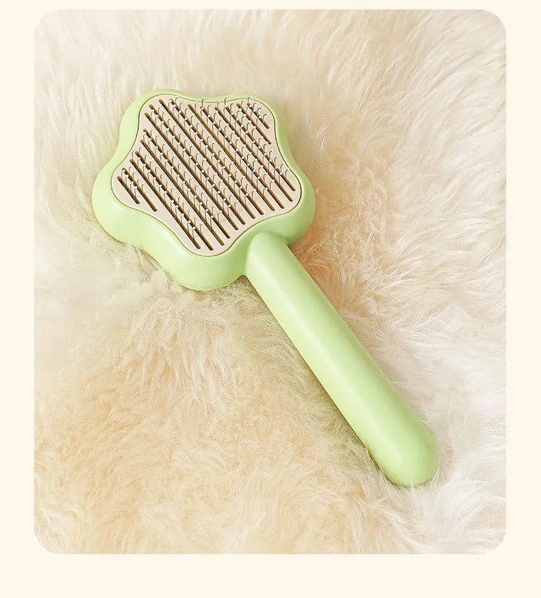 Green self-cleaning cat comb with stainless steel needle pins on a white background