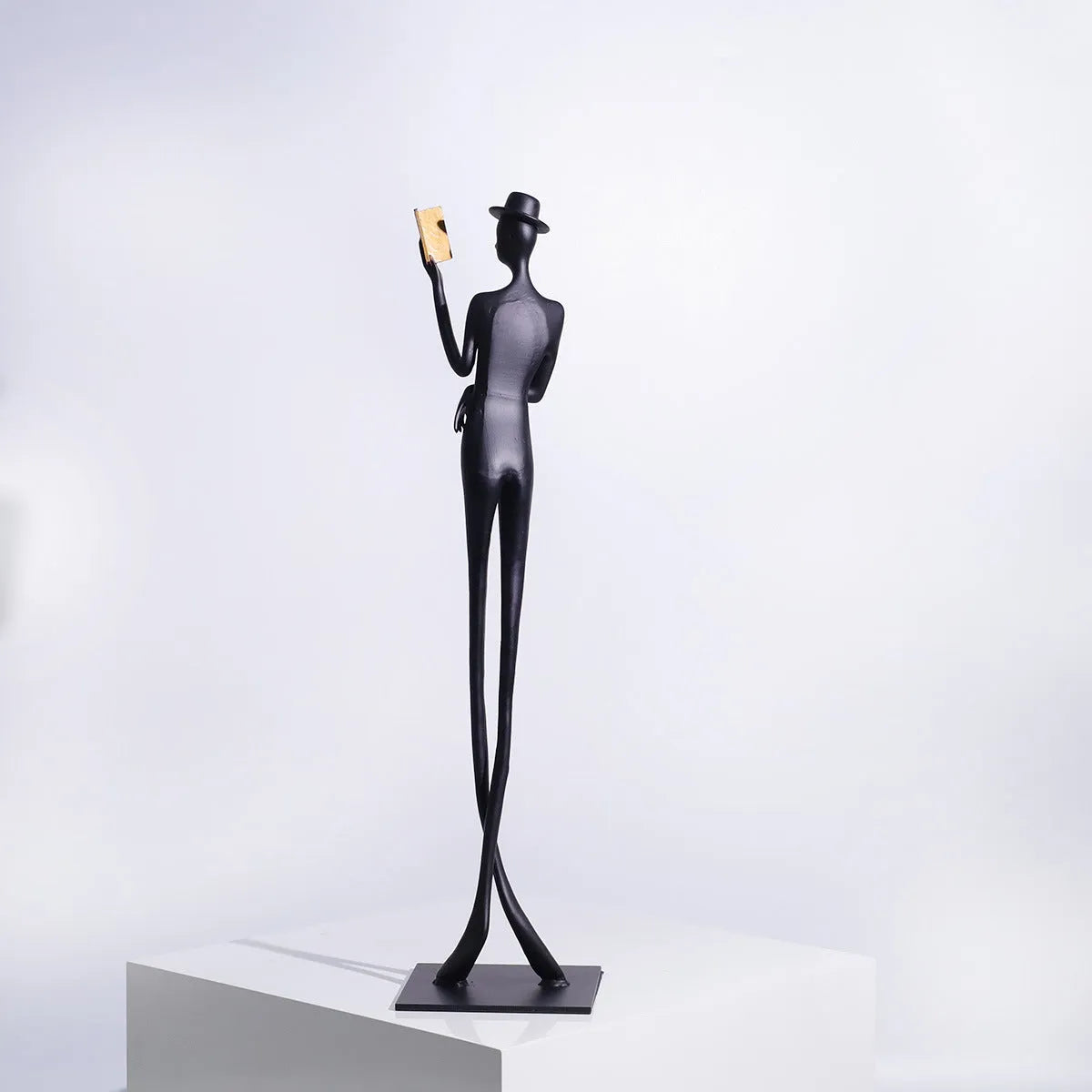 Black cast aluminium reading woman sculpture on desktop, 12 cm wide by 51 cm high