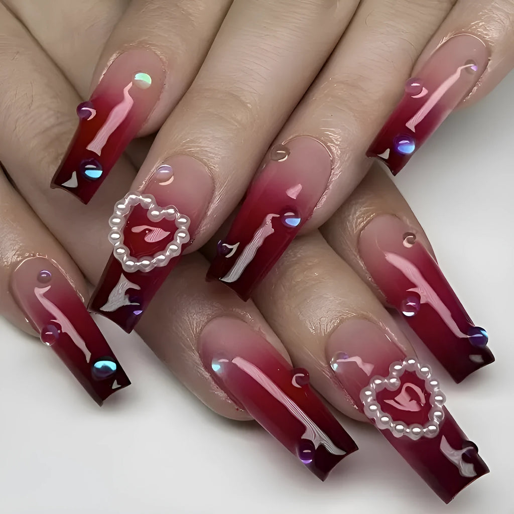Wine red gradient fake nail tips with pearl heart design in a long ballet style.