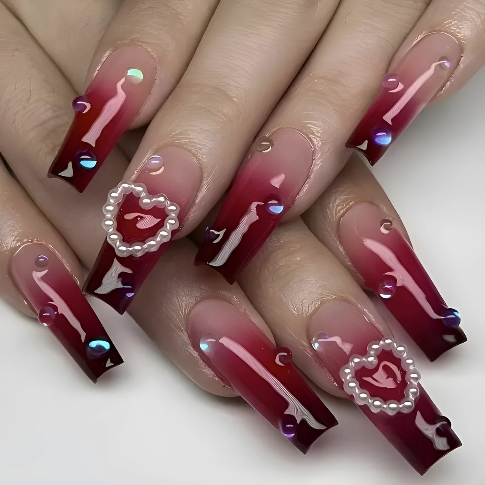 Wine red gradient fake nail tips with pearl heart design in a long ballet style.
