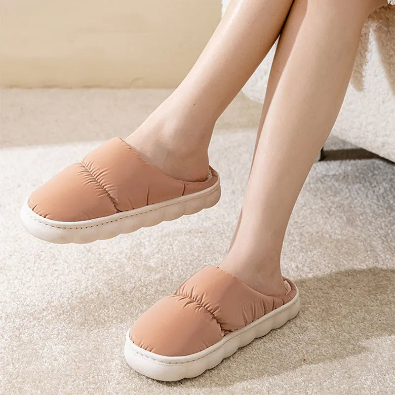 Blue down cotton indoor slippers with thick rubber sole and plush lining, shown on a wooden floor.