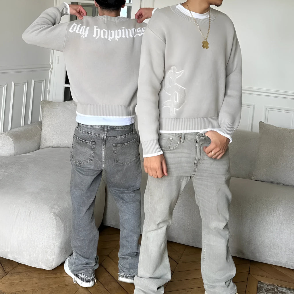 Grey loose-fitting jacquard knit pullover coat with long sleeves on a hanger.