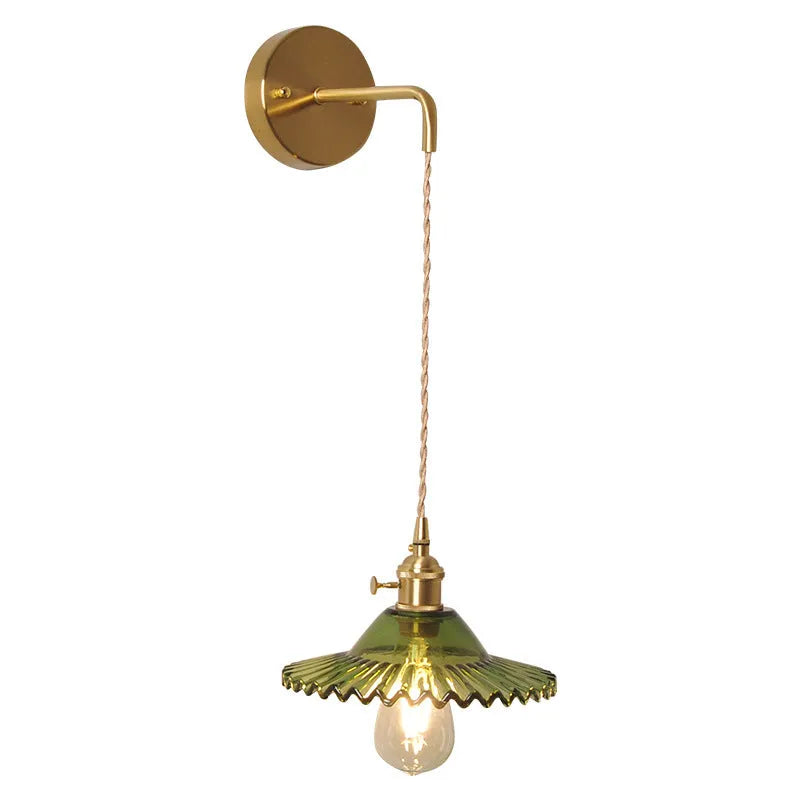 Brass lotus-shaped wall lamp with glass shade in choice of six colours on a plain wall.