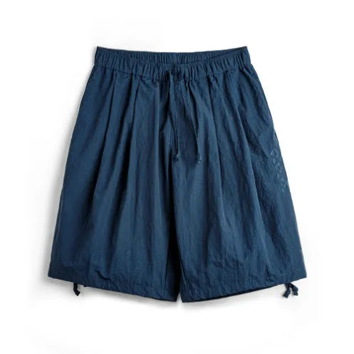 Men's loose fit Prussian blue nylon beach shorts with summer embroidery on a white background.