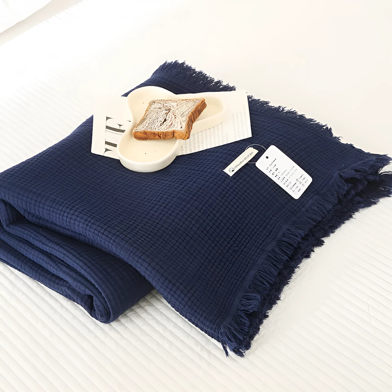Four-layer gauze cotton blanket with tassel trim in avocado green colour draped over a sofa