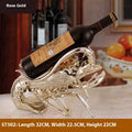 Lobster-shaped decorative wine rack ornament in metallic rose gold holding a wine bottle.