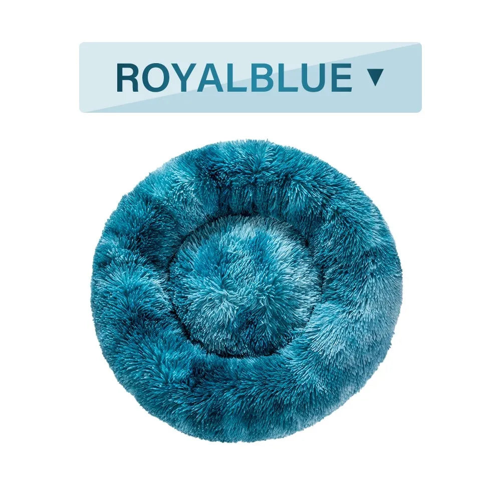 Fluffy donut-shaped dog bed in long plush fabric, shown in a light grey colour with a raised edge.