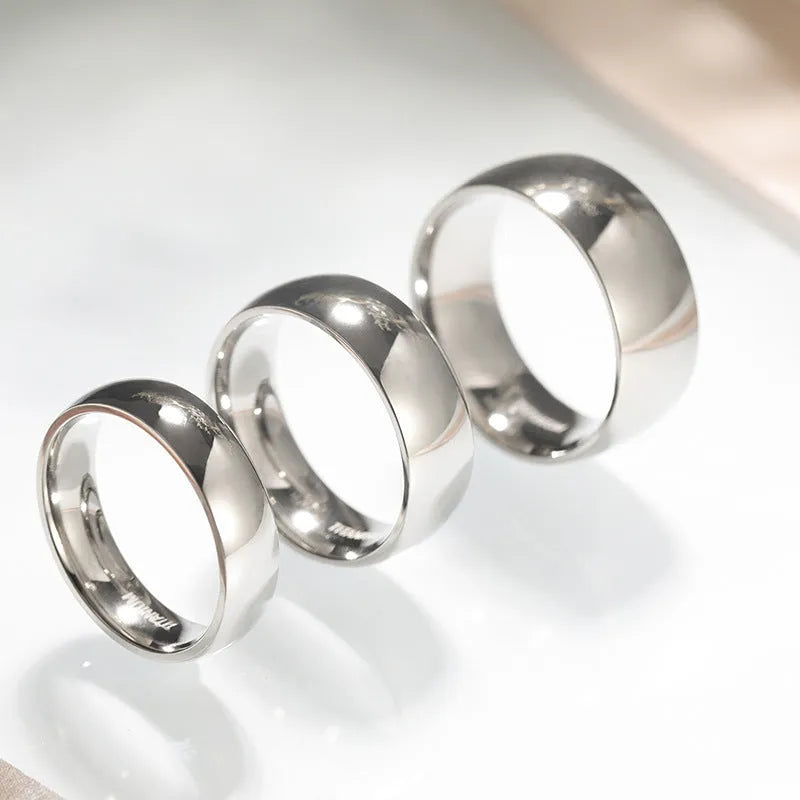Polished silver titanium steel ring on a finger, showing a minimalist band design.