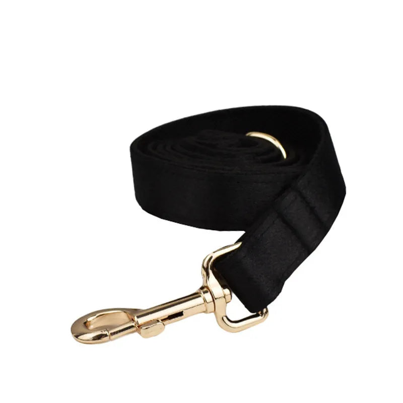 A soft cloth dog collar, leash, bow, and matching chest strap set laid out flat, showing coordinated colours.