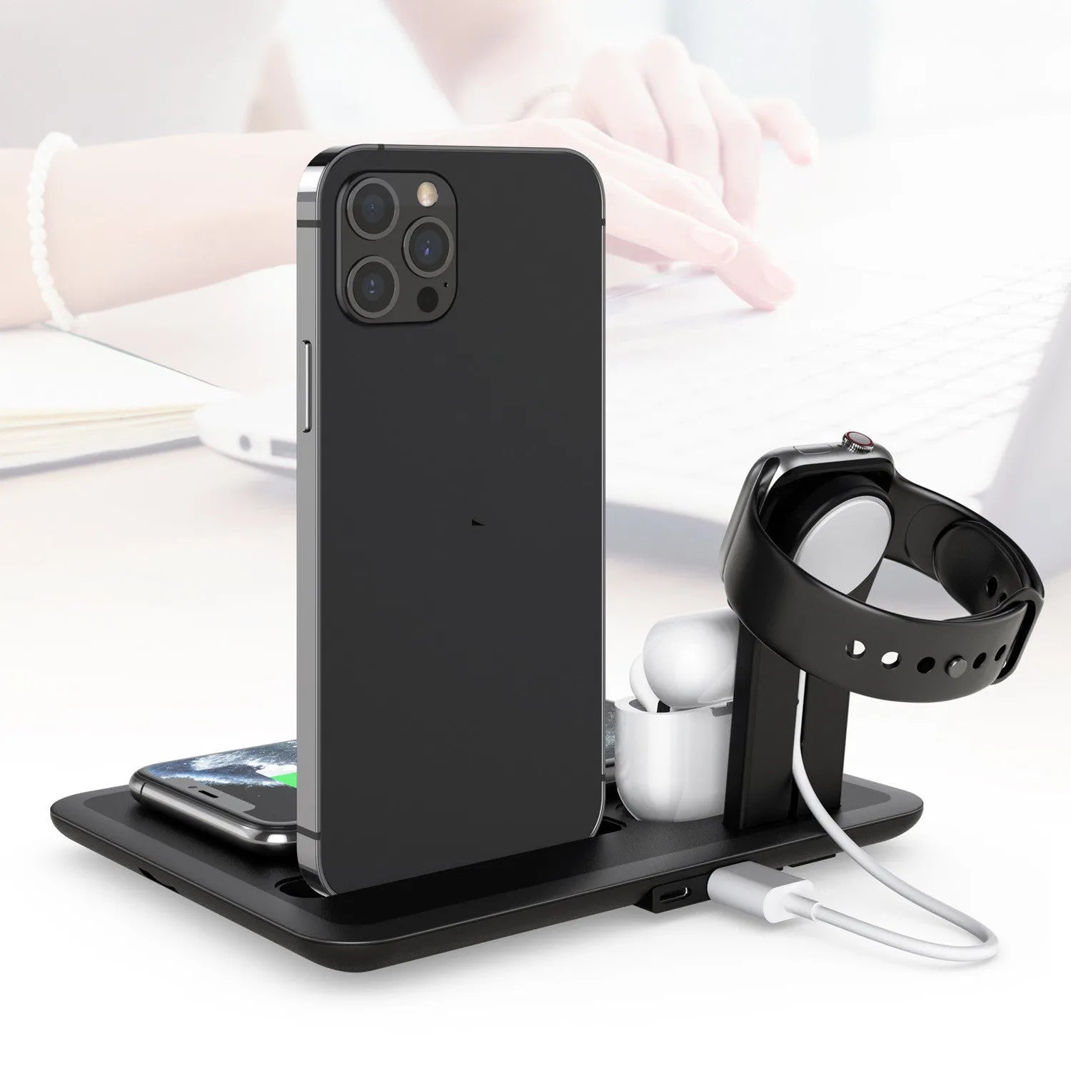 Black and white wireless desktop charging station for phone, headphones and watch on a desk