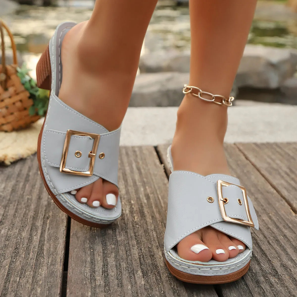 A pair of women's black retro-style slippers with a chunky heel and a prominent silver metal buckle across the instep.