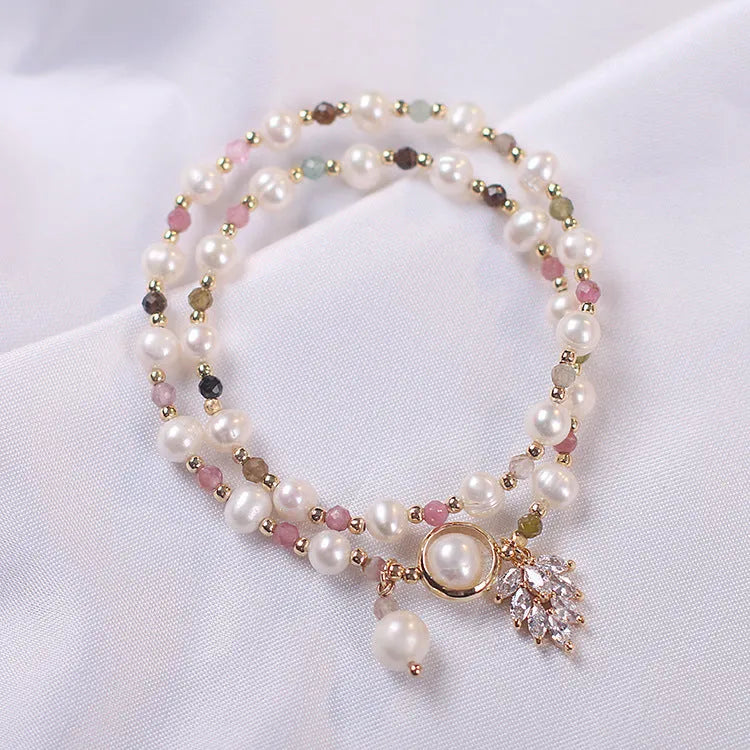 Women's double-layer strawberry quartz crystal bracelet with a red lucky cat charm on a white background.