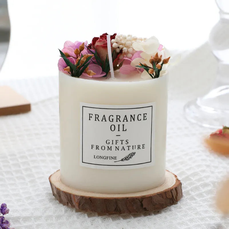 Aromatherapy candle decorated with dried flowers on top, shown in gift box packaging with a wood base.