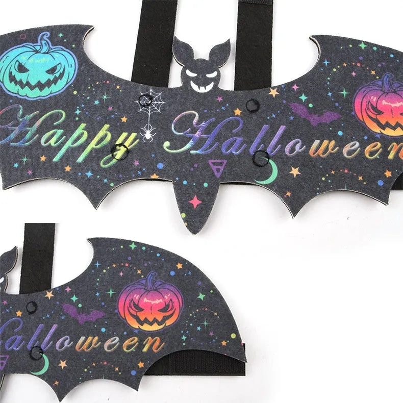 Black cat wearing an orange felt batwing Halloween costume with bell attachment.