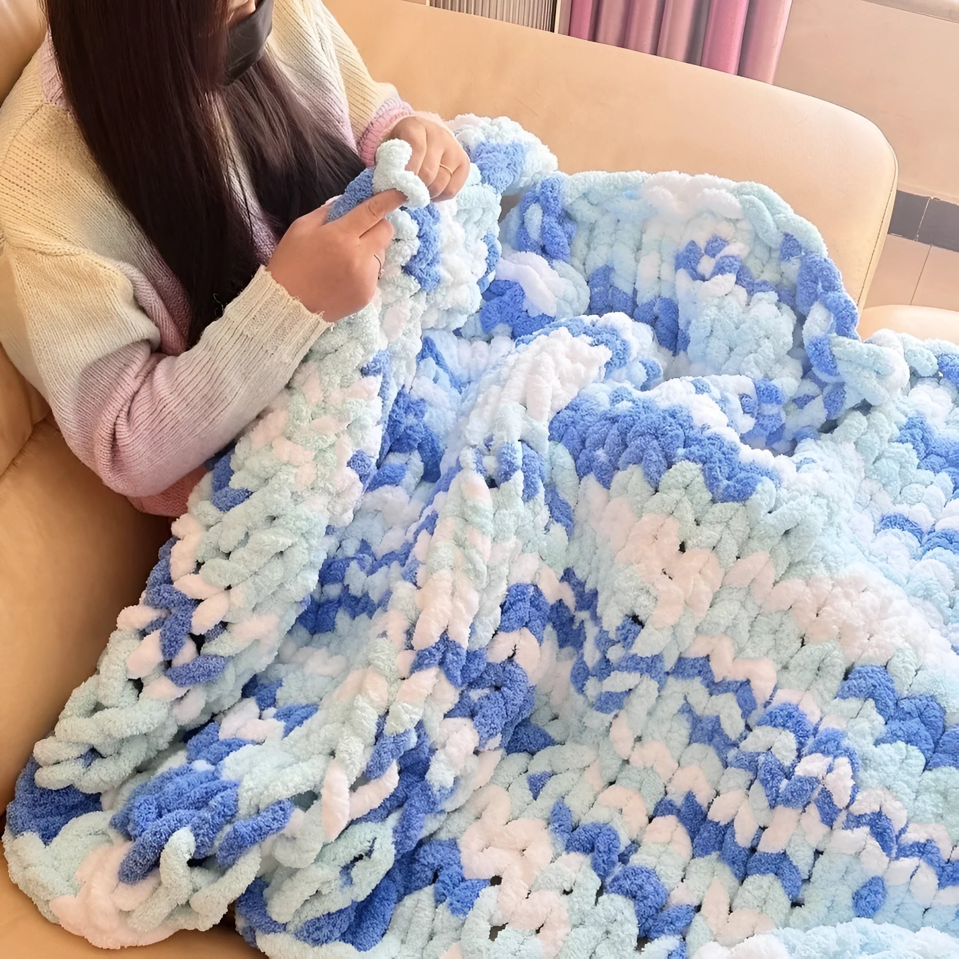 Coarse yarn chenille knitted blanket with braided gravity trim in a modern colour on a bed.