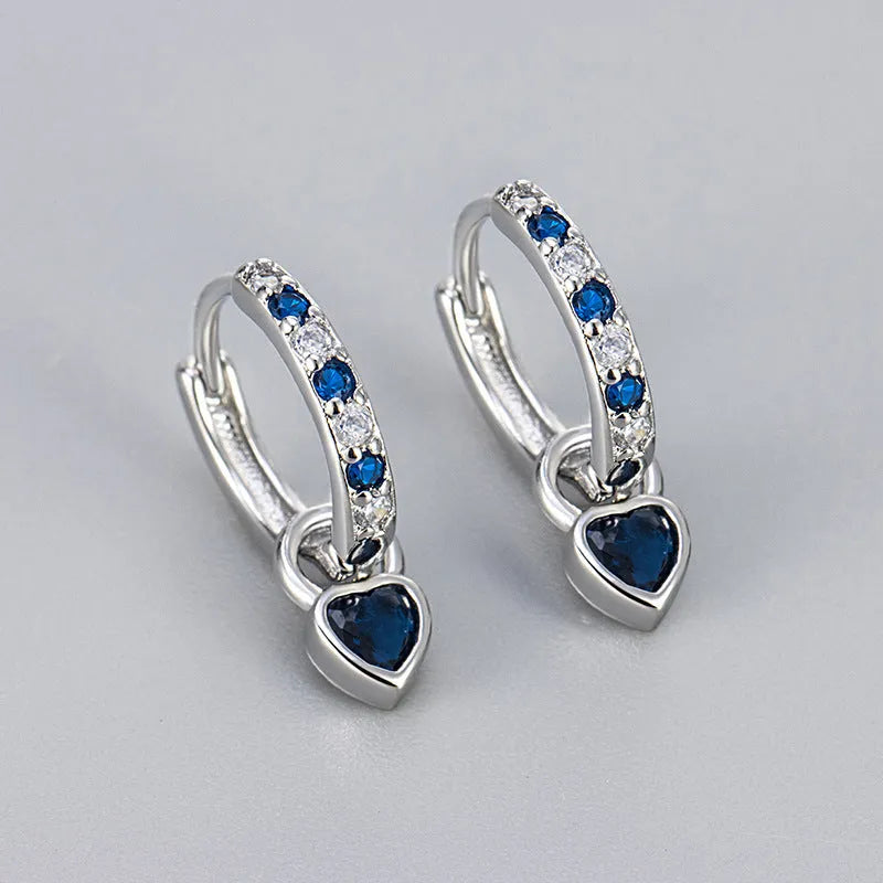 A pair of women's heart-shaped clip earrings with a coloured gemstone centre, available in gold or white gold colour metal.