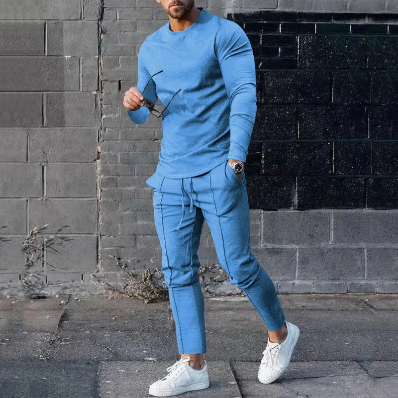 Man wearing a light grey round-neck long-sleeve t-shirt and matching trousers from a two-piece polyester suit set.