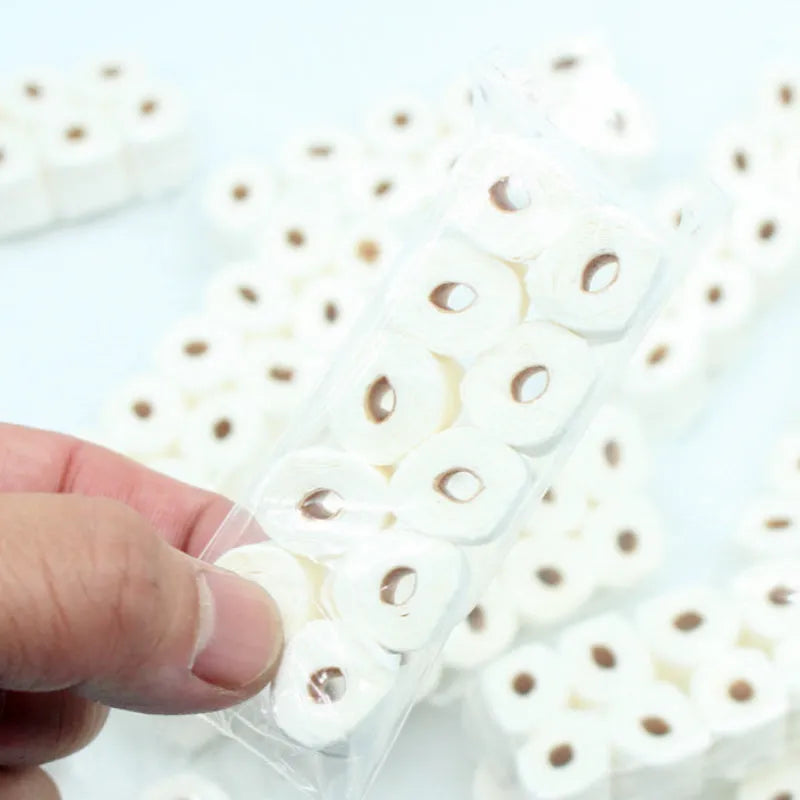 Small-scale simulated toilet paper roll model made of paper, shown next to a ruler for scale.