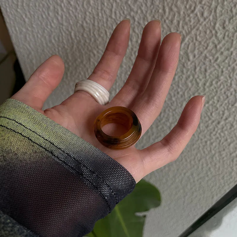 Geometric irregular resin wide ring in brown and white colours on a plain background.